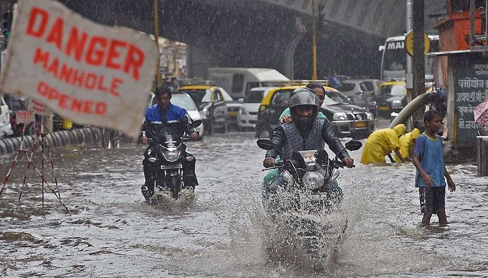 Vehicles wade through a water logged road after heavy rains in Mumbai.