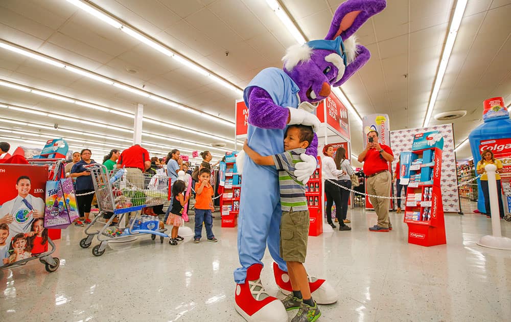 A child embraces a giant purple bunny rabbit at Colgate Oral Health Month at Fiesta Supermarket, in Houston. 