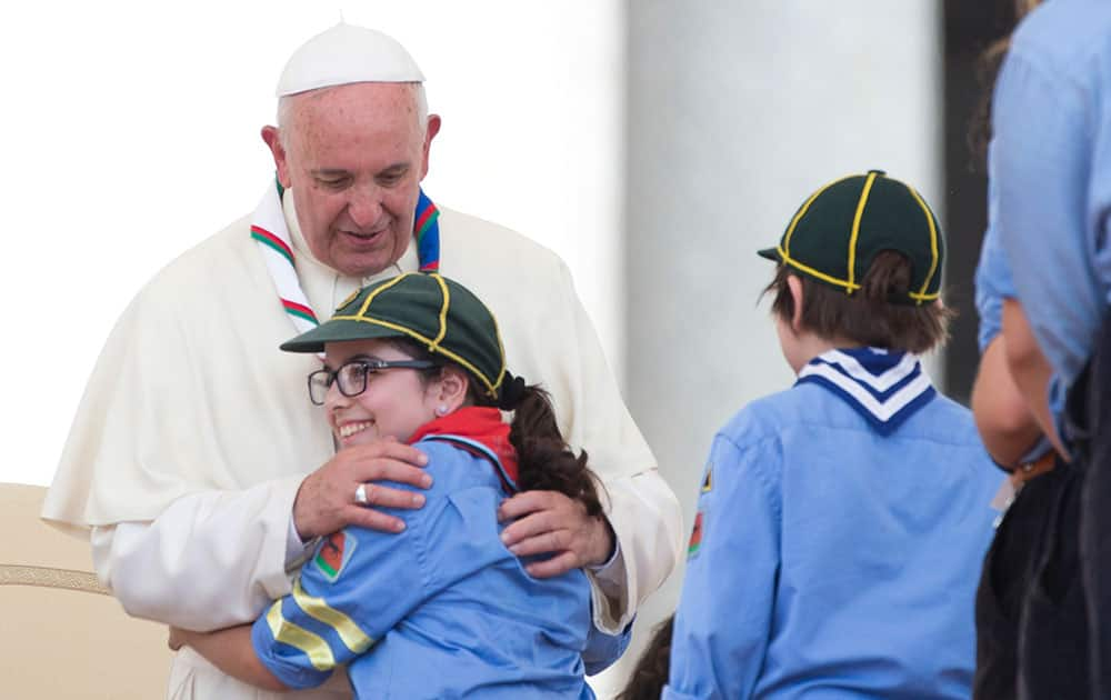 Pope Francis hugs a girl at the end of an audience with Italian AGESCI boy scouts association's members in St. Peter's Square at the Vatican.