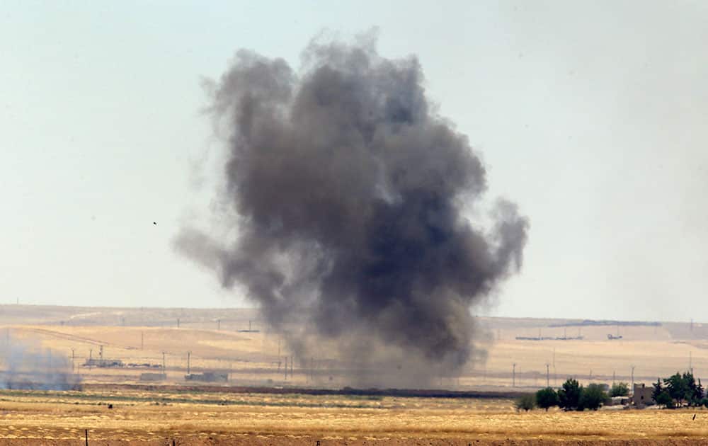 southeastern Turkey from the Turkish side of the border between Turkey and Syria, smoke from a US-led airstrike rises over the outskirts of Tal Abyad, Syria.