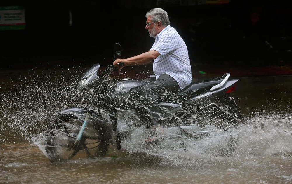 A  man rides a bike through a water-logged street as it rains in Mumbai, India.