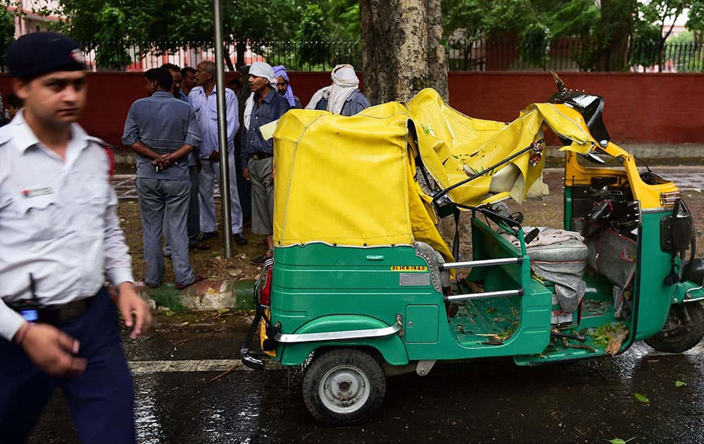 An autorickshaw that was crushed under a fallen tree at a road during a storm in New Delhi.