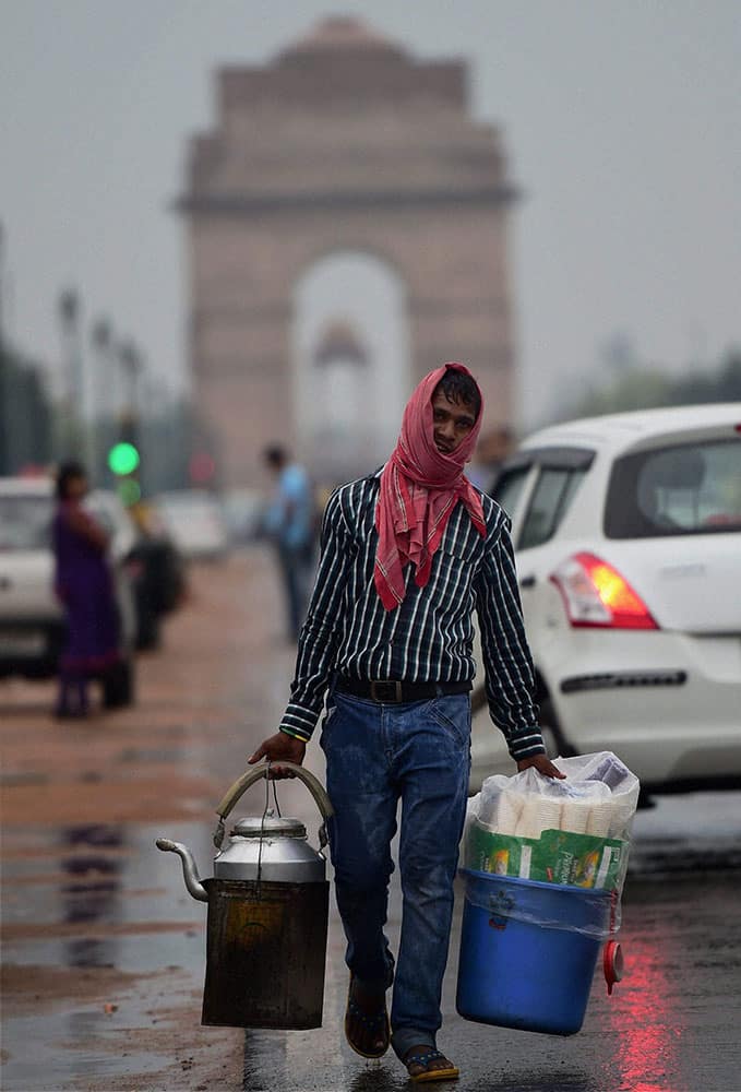 A tea vendor walks along Rajpath after rains in New Delhi.