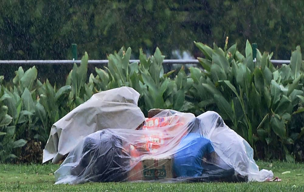 People cover themselves with a polythene during a storm accompanied by shower in New Delhi.