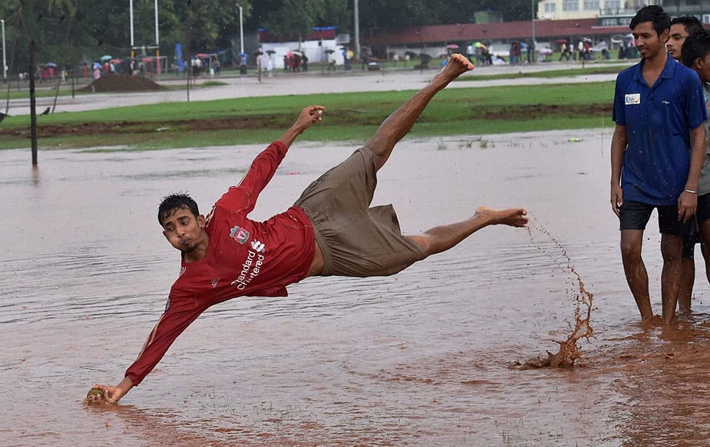 Boys play in the rain water at Azad Maidan in Mumbai.