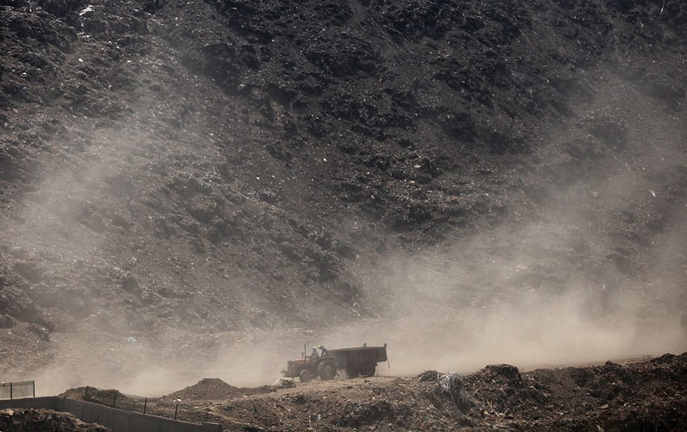 Dust rises as a tractor passes after dumping garbage at a waste yard on the outskirts of New Delhi.