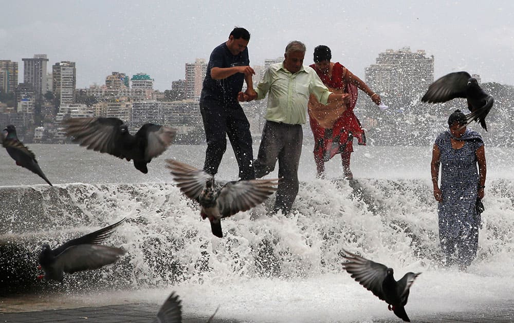 People try to walk away as huge tidal waves hit the Arabian Sea shore marking the arrival of monsoon season in Mumbai.