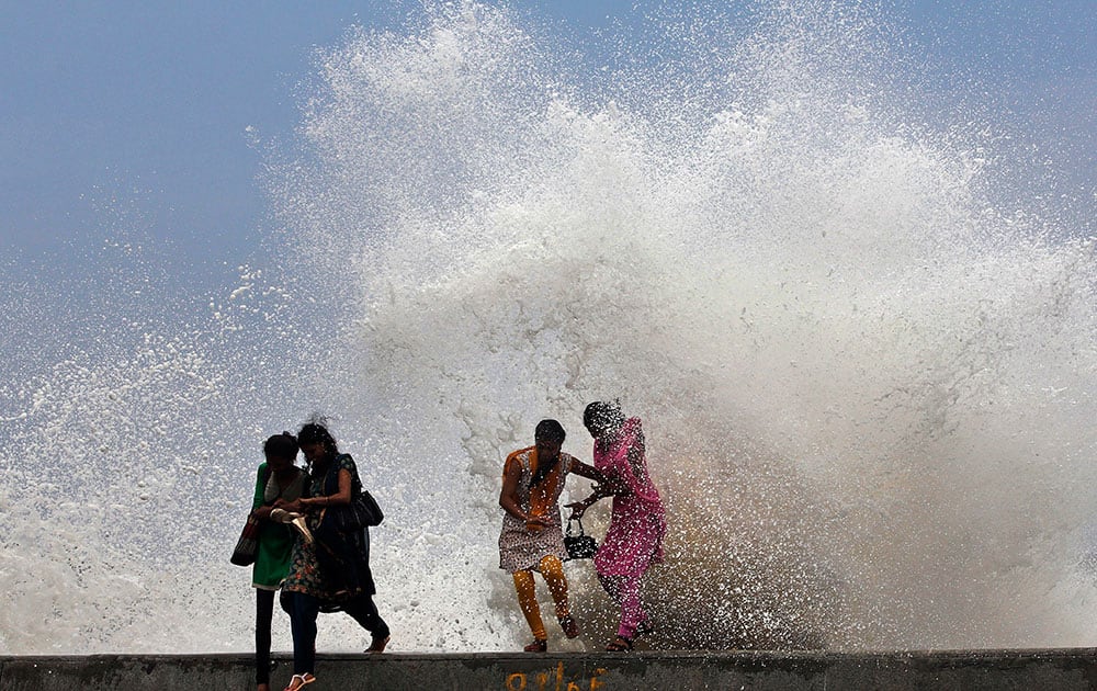 girls enjoy high tide waves marking the arrival of monsoon season on the Arabian Sea coast in Mumbai.