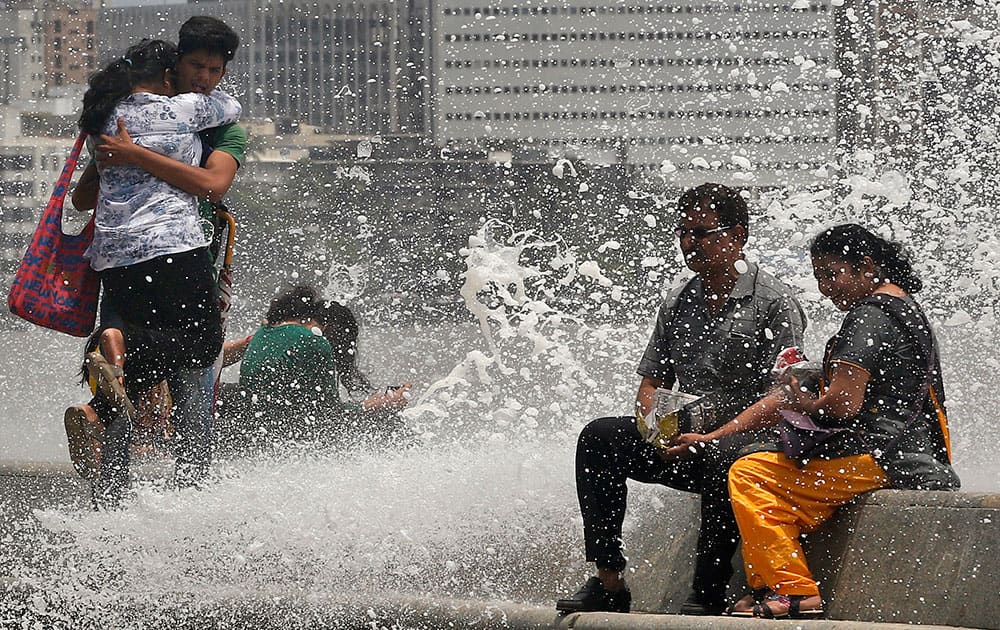 people get drenched from a wave that hit the shore during high tide at the Arabian Sea coast marking the arrival of monsoon season in Mumbai.