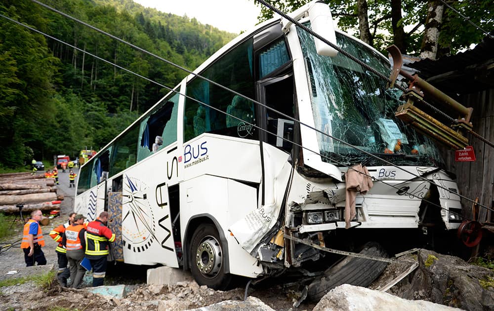 Rescue workers stands beside a crashed bus between Engelberg and Wolfenschiessen in the canton of Obwalden, Switzerland. Several passengers from China were injured.