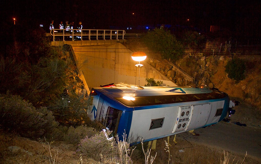 A bus lies by the side of a highway after it went off the road and rolled over into a gully Wednesday night, near the town of Albufeira in southern Portugal's Algarve region. Portuguese officials said that the bus was carrying 33 Dutch tourists who had arrived at the Faro airport.