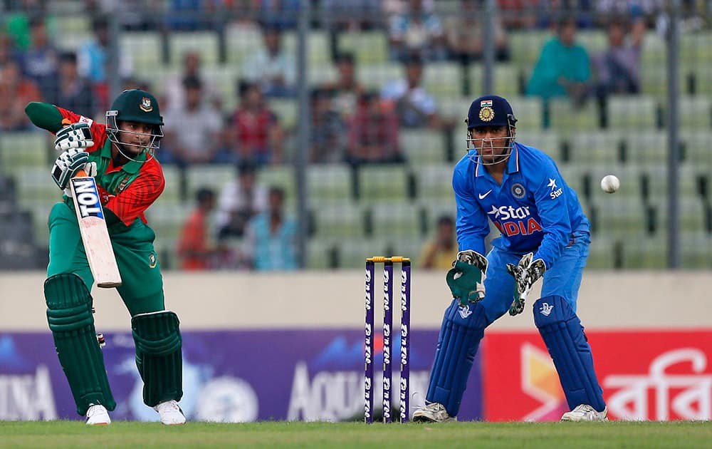 Shakib Al Hasan plays a shot as wicketkeeper MS Dhoni watches during the first one-day international cricket match between them in Dhaka, Bangladesh.