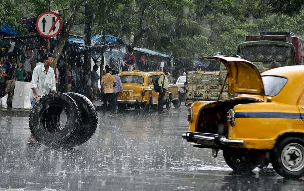 A man rolls truck tires to a waiting taxi during monsoon rains in Kolkata.