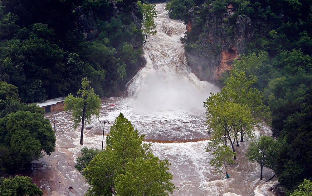 Water pours over Turner Falls and floods the park below, in Davis, Okla.