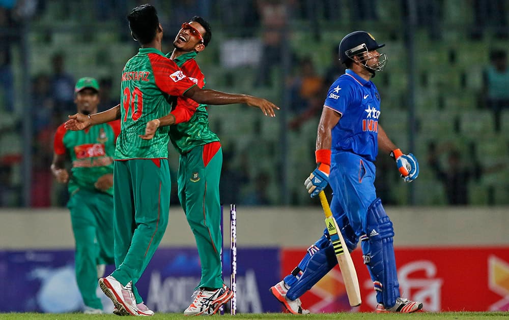 Bangladesh’s Mustafizur Rahman, left, celebrates with teammate Nasir Hossain, center, the dismissal of India’s Suresh Raina, right, during the first one-day international cricket match between them in Dhaka.