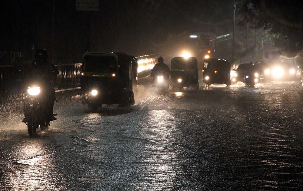 Vehicles wade through a water logged road after heavy rains.