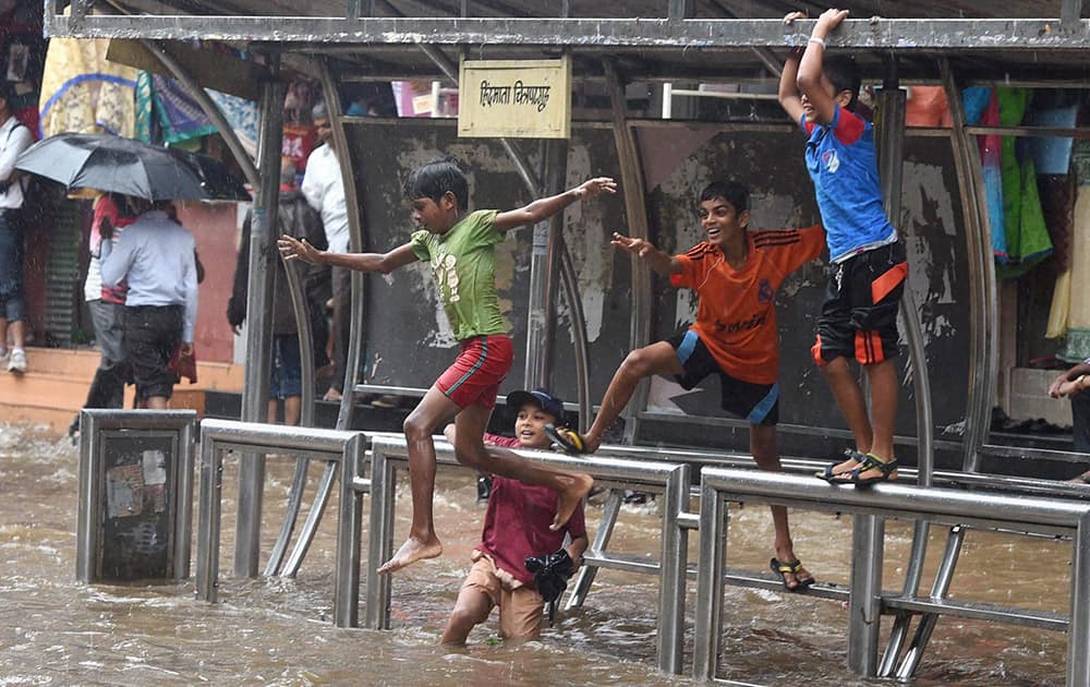 Children enjoying at a water logged road as it rains in Mumbai.