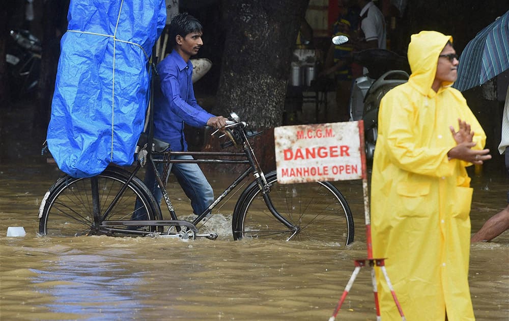 People wade through a water logged road after heavy rains in Mumbai.