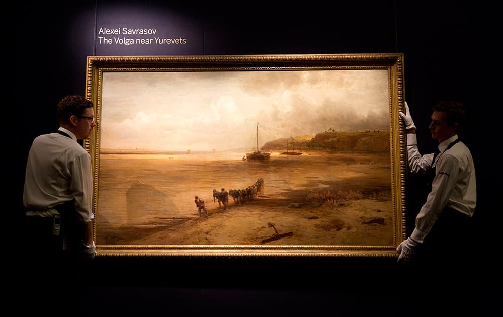 Sotheby's workers pose for photographs with the Alexei Savrasov oil on canvas entitled 'The Volga near Yurevets' at premises of the auction house in London.