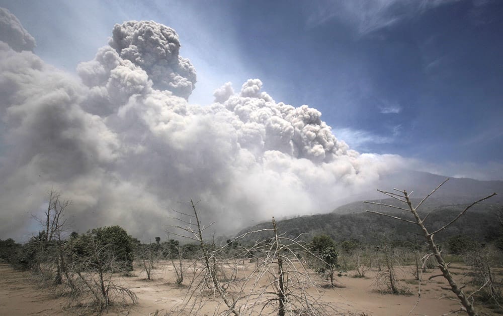 Mount Sinabung releases pyroclastic flows as seen from a coffee plantation affected by the volcano's previous eruption in Sigarang Garang, North Sumatra, Indonesia.