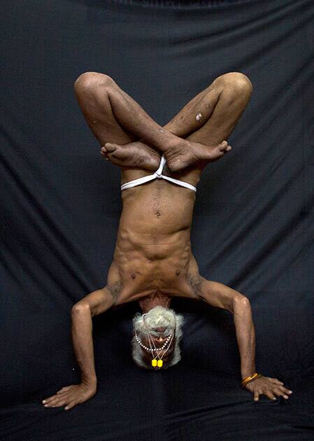 Hindu holy man, illustrates the yoga pose Ardha Sirasana, where the yogi lies on his back and puts his crossed legs in the air, in Guwahati.