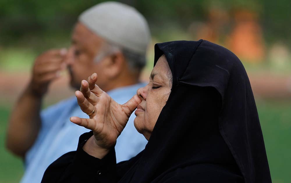 A Muslim woman and a man perform yoga at a garden in Ahmadabad.