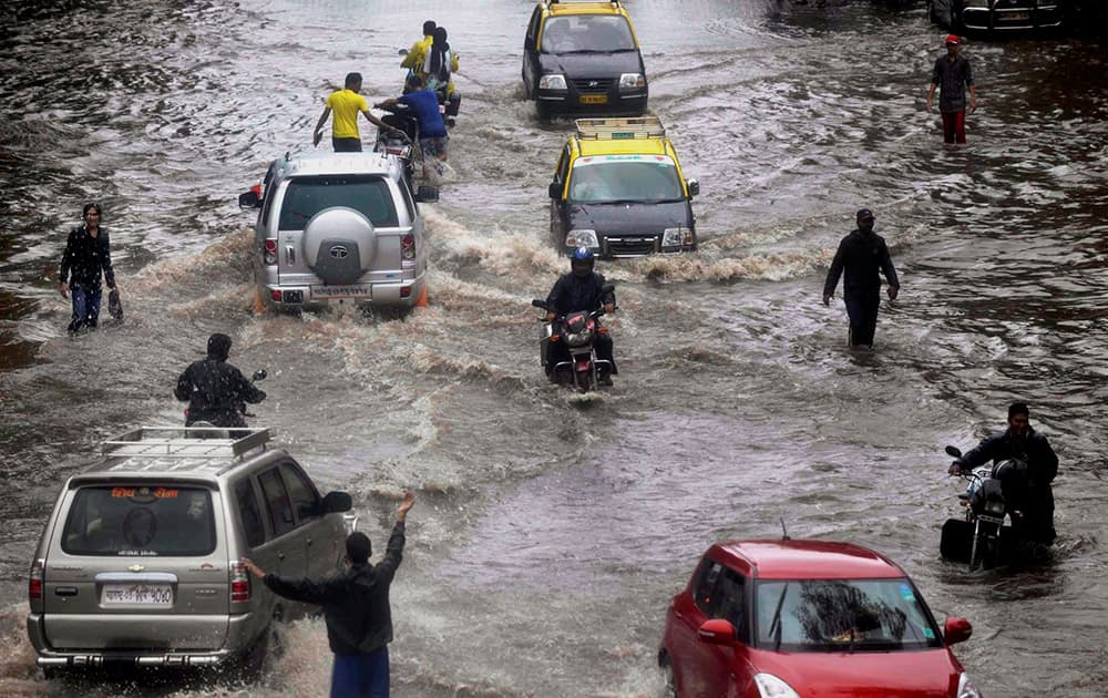 People wade through a water logged road after heavy rains near Dadar in Mumbai.