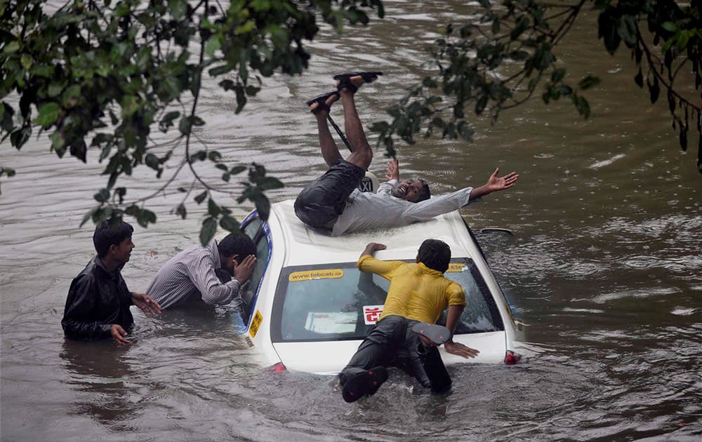 A vehicle stuck in rain water at a road as boys having fun after heavy shower in Mumbai.