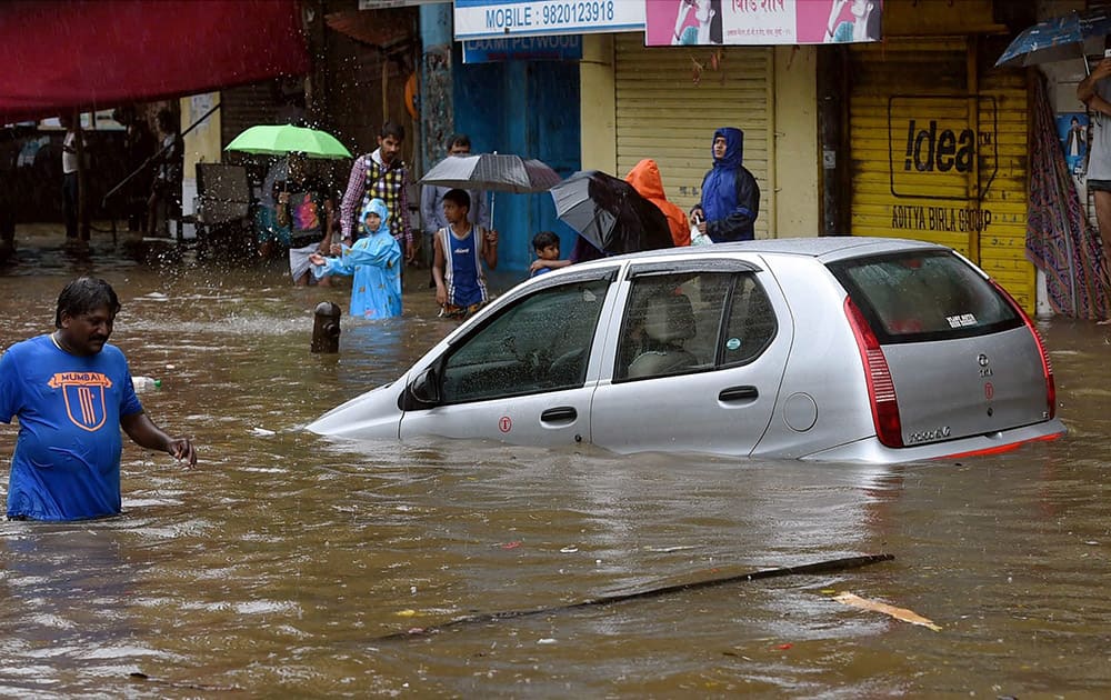 People wade through a water logged road after heavy rains in Mumbai.