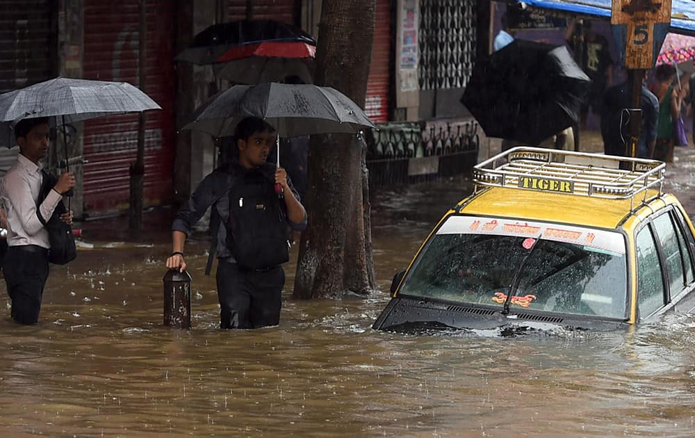 People wade through a water logged road after heavy rains in Mumbai.
