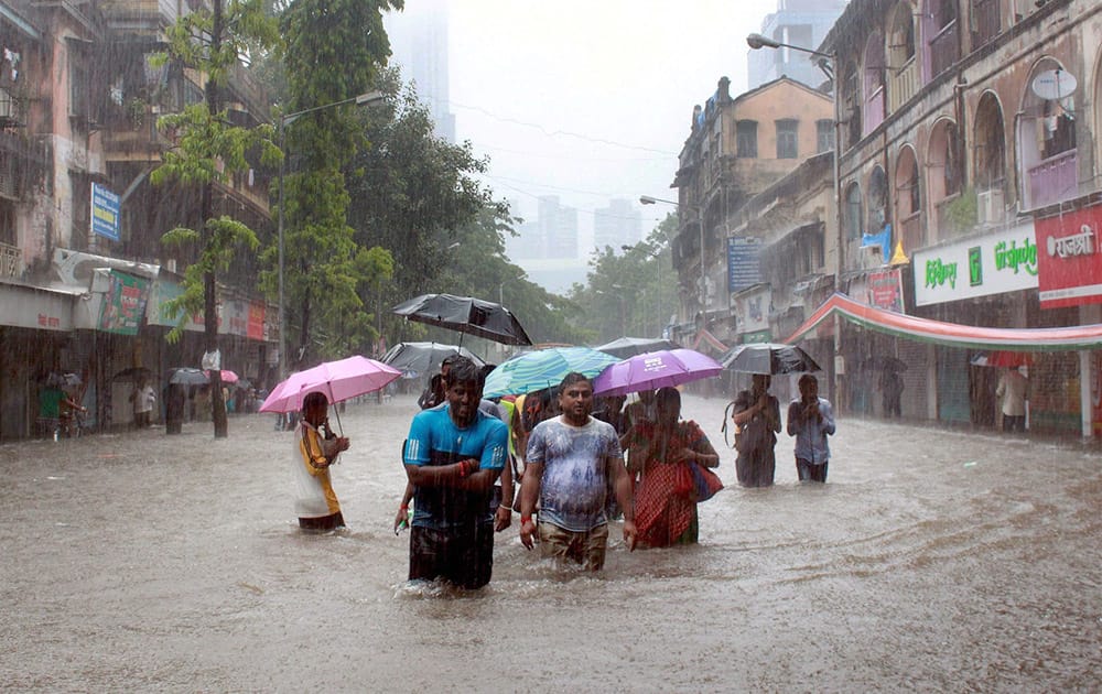 People wade through a water logged road after heavy rains in Mumbai.