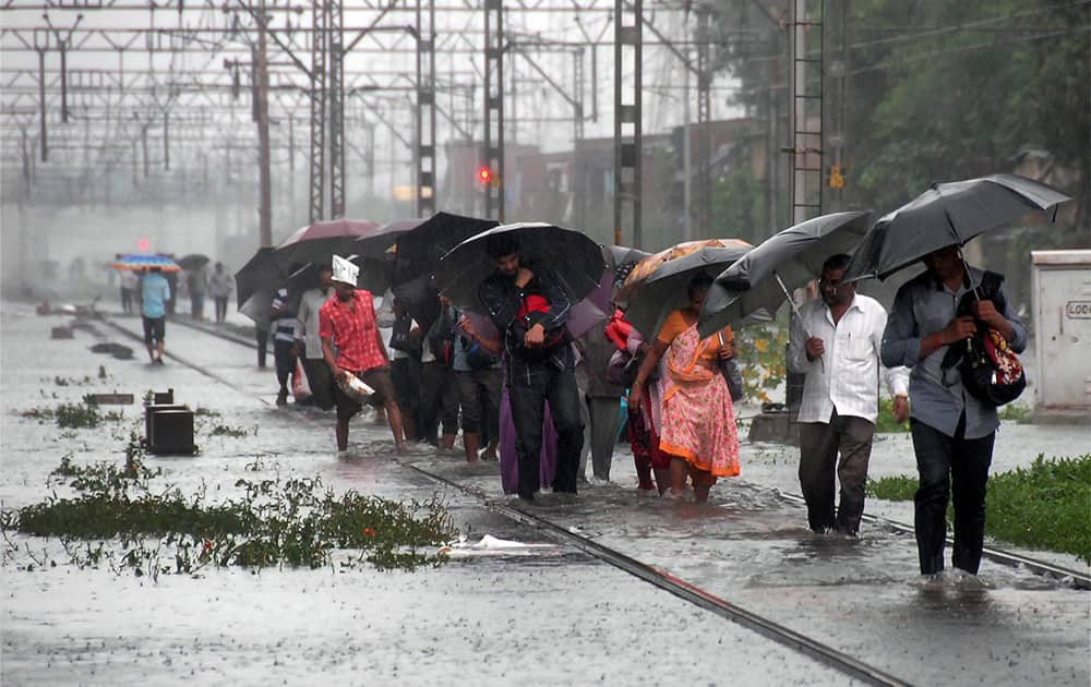 People walk through flooded railway tracks after heavy rains in Mumbai.