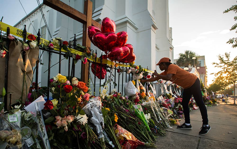 A mourner places flowers along the fence outside the Emanuel AME Church in Charleston, S.C. 