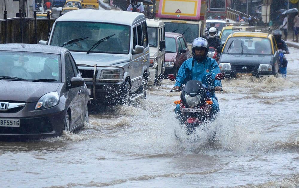 People wade through a waterlogged road after heavy rains on second consecutive day in Mumbai.