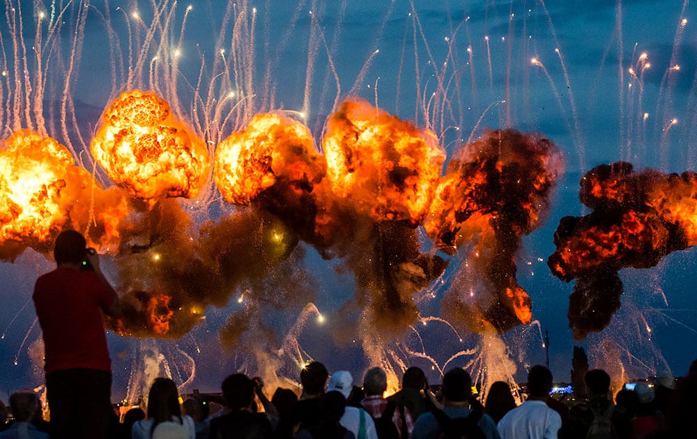 people are silhouetted by a pyrotechnic display at the end of an international air show in Bucharest, Romania. 