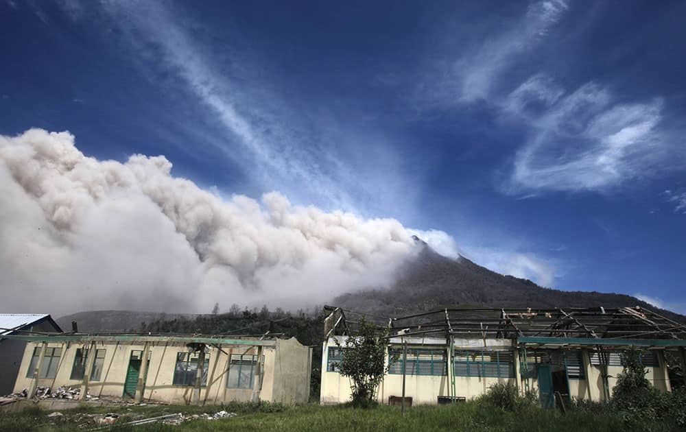 Mount Sinabung releases pyroclastic flows as a school building affected by the volcano's previous eruption is seen in the foreground in Sigarang Garang, North Sumatra, Indonesia.