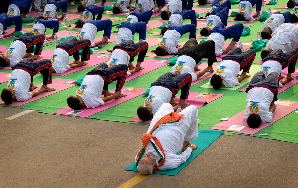 Prime Minister Narendra Modi, center front, performs yoga along with thousands of Indians on Rajpath, in New Delhi, India.