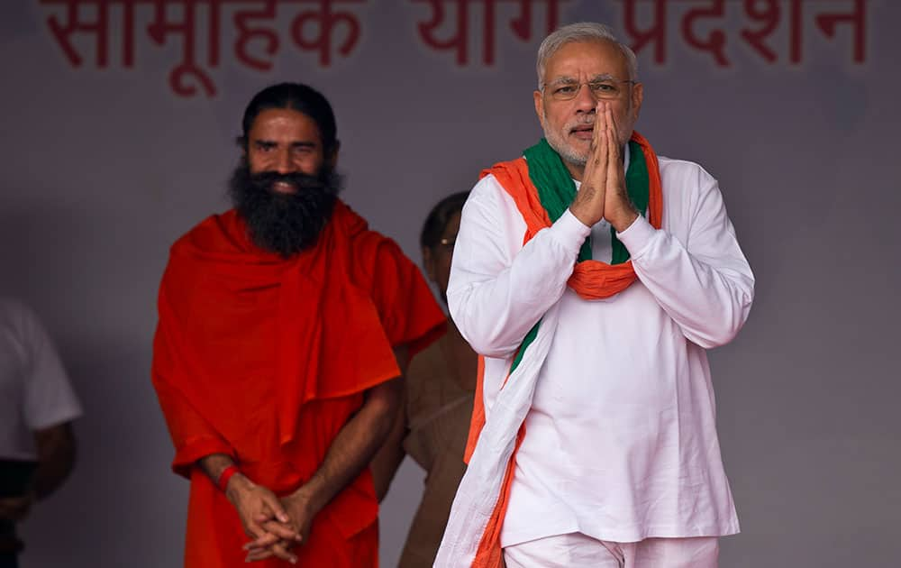 Prime Minister Narendra Modi, right, greets people as he arrives to attend a mass yoga performance on Rajpath, in New Delhi, India.