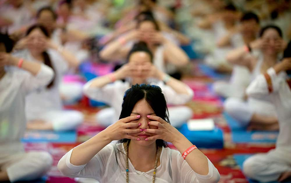 Chinese perform yoga under the instructions of Indian yoga teachers at a hotel banquet hall to mark the International Yoga Day, in Changping District, on the outskirts of Beijing, China.