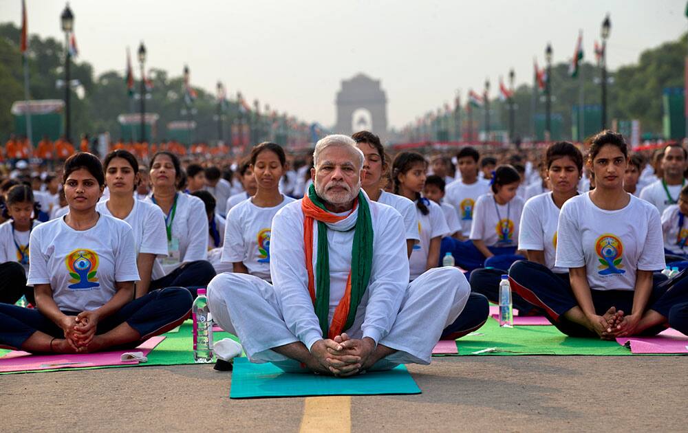 PRIME MINISTER NARENDRA MODI, CENTER, SITS ON A MAT AS HE PERFORMS YOGA ALONG WITH THOUSANDS OF INDIANS ON RAJPATH, IN NEW DELHI, INDIA.