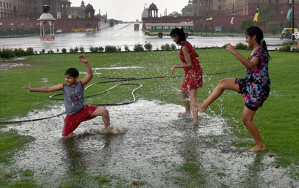 Children play in rain water at Vijay Chowk lawn in New Delhi.