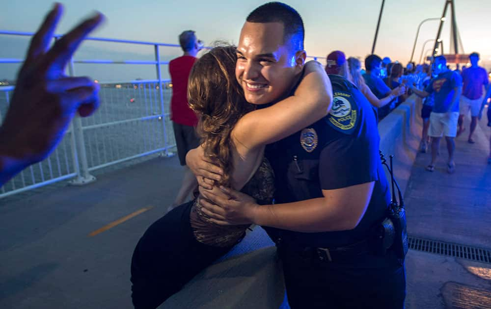 Mt. Pleasant Police Officer Brandon Montano gets high-fives and hugs as thousands of people march across of Charleston's main bridge in a show of unity after nine black church parishioners were gunned down during a Bible study, in Charleston, S.C. 