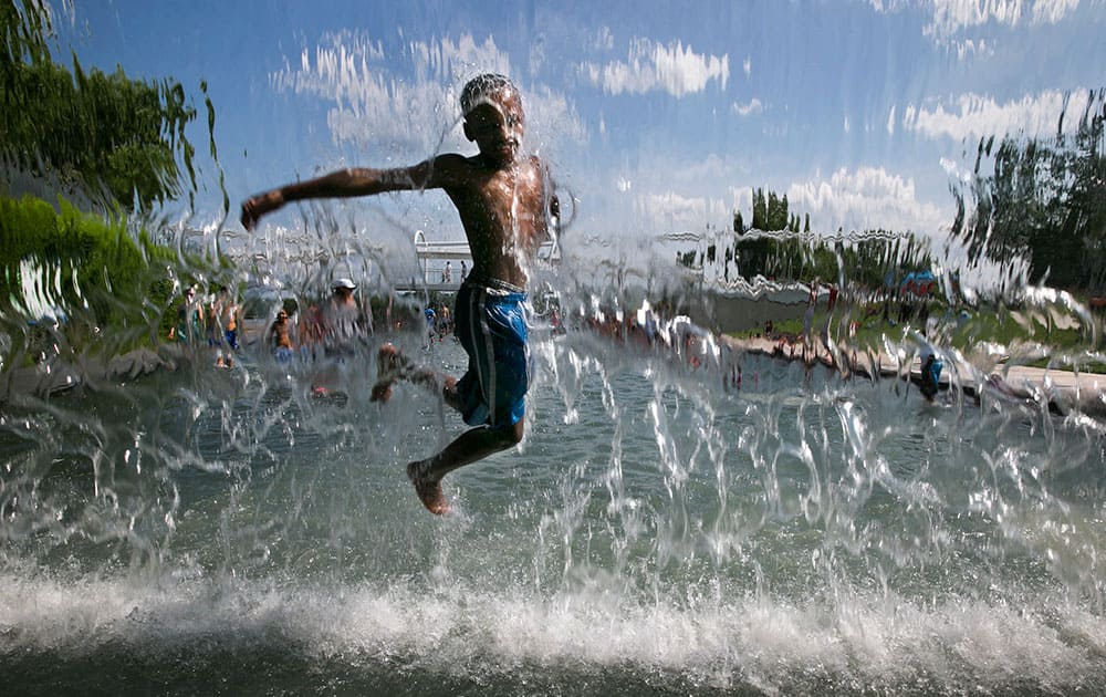 David Lawrence, 8, of Washington, leaps through a waterfall feature at Yards Park on the first day of summer, in Washington. 