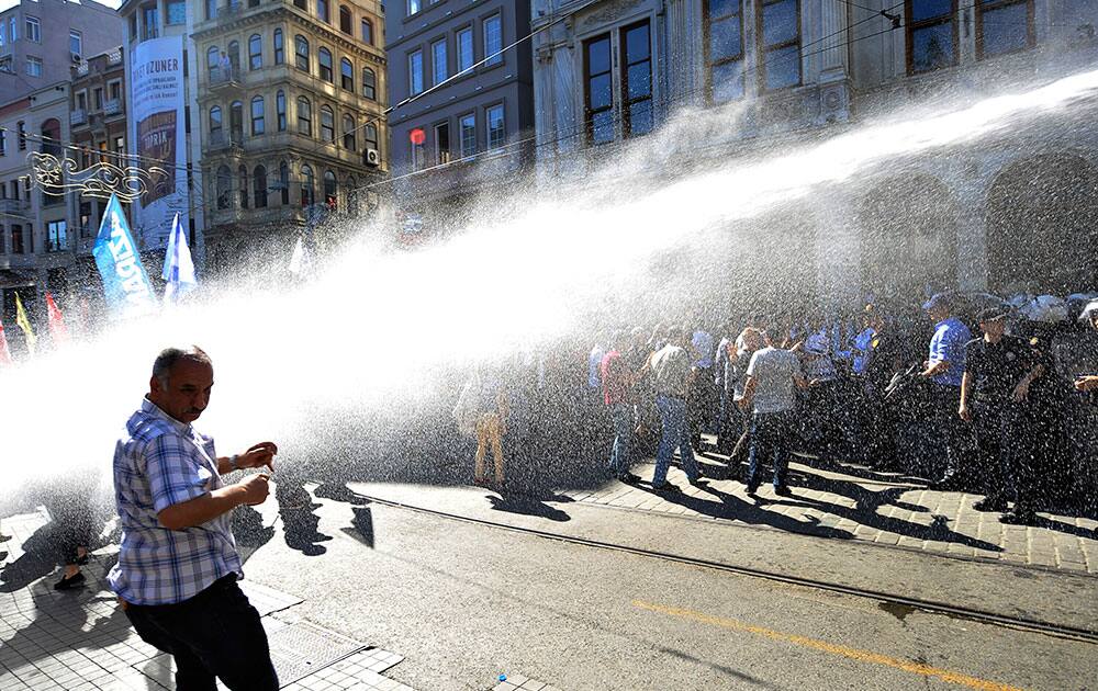 An anti-government protester from the left-wing United June Movement (BHH) tries to protect himself from water, sprayed by a police water canon truck, in order to disperse them in Istanbul, Turkey.