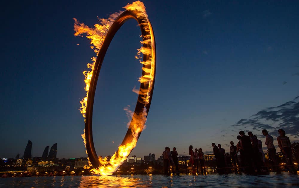 People walk near the giant ring with the flame of the 2015 European Games at the embankment of Caspian Sea in Baku, Azerbaijan.