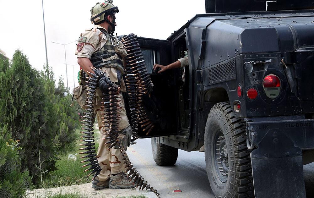 Afghan security personal load a military vehicle at the site of a suicide attack during clashes with the Taliban fighters in front of the Parliament, in Kabul, Afghanistan.