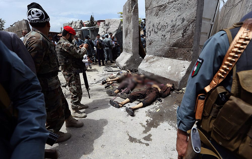 Afghan security forces stand guard near to the dead bodies of Taliban attackers after clashes in front of the Parliament, in Kabul, Afghanistan.