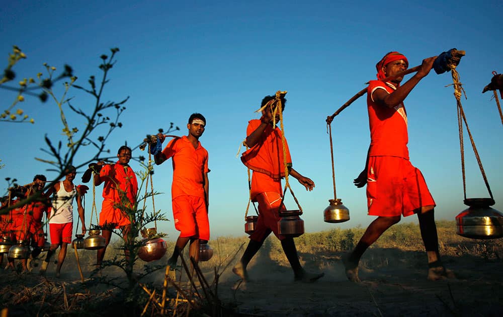 Kanwarias, worshippers of Hindu God Shiva, carry metal canisters filled with holy water from the Ganges River as they walk towards Padilla Mahadev temple, on the outskirts of Allahabad, India.