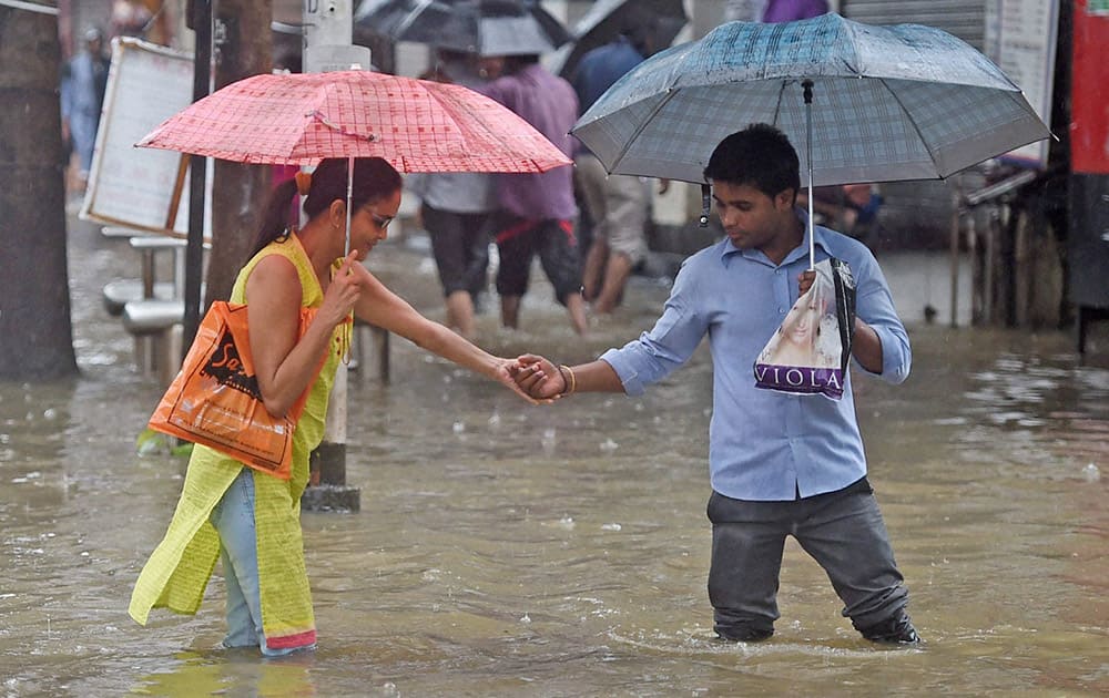 People wade through a water logged street after heavy downpour in Mumbai.