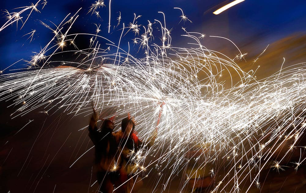 Revelers hold fireworks as they take part in 'Correfoc' (Run with fire) party during the night of San Juan in Barcelona, Spain.